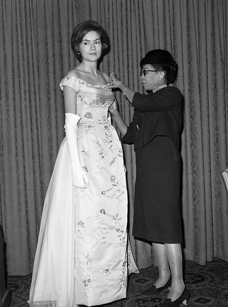 Remaining in the background of the fashion world for 35 years in New York, Ann Lowe, had her first show this year. The designer, adjusting the bodice of a gown she designed and worn by Alice Baker, has fitted most of the debutant and wedding dresses of the nation's top families which include Jackie Kennedy. The nimble-fingered designer held her show in New York and her models were all "silver spoon" girls--all old friends and devoted customers. (Photo by Bettmann Archive/Getty Images)