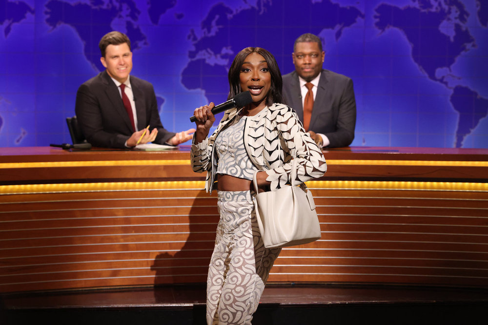 SATURDAY NIGHT LIVE -- Episode 1884 -- Pictured: (l-r) Anchor Colin Jost, Ego Nwodim as Miss Eggy, and anchor Michael Che during Weekend Update on Saturday, May 17, 2025 -- (Photo by: Will Heath/NBC)