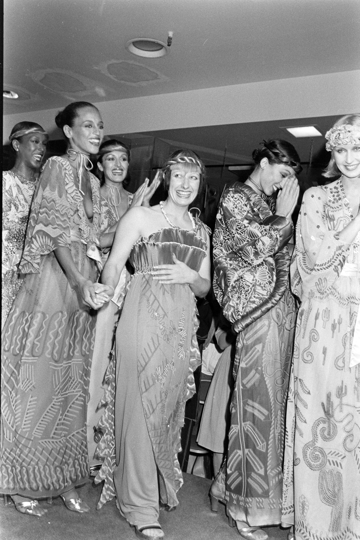 Zandra Rhodes with models Pat Cleveland, Alva Chinn, Carla Araque, Chris Royer, and Billy Blair in looks from her fall 1976 'Fantasies' collection.