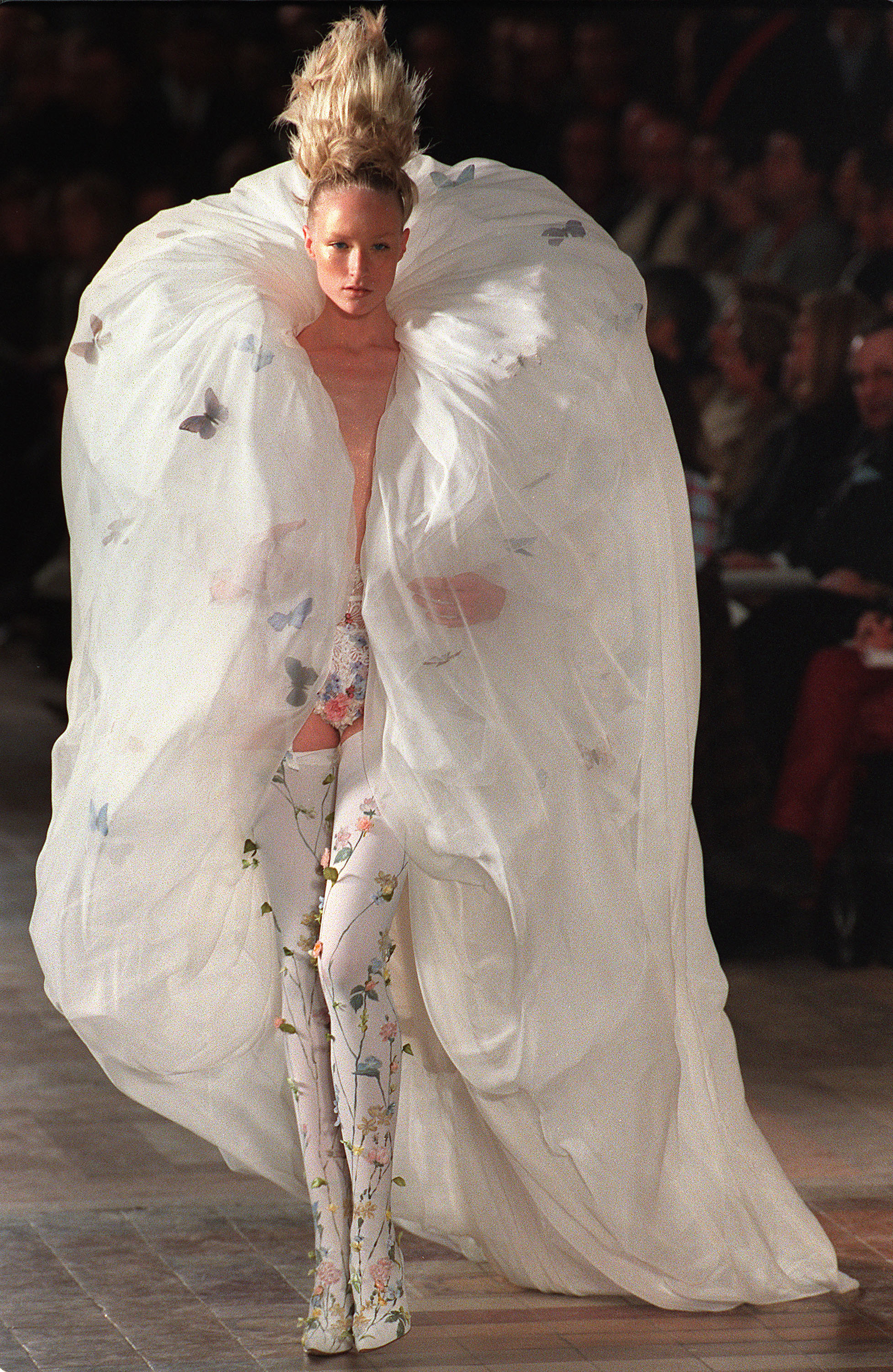 La mannequin britannique Jade Parfitt du couturier Alexander McQueen pour Givenchy présente une robe de mariée avec des motifs papillons, le 19 janvier à Paris, dans le cadre des défilés de haute-couture printemps-été 97.
British model Jade Parfitt sports a big white organza coat with hand painted