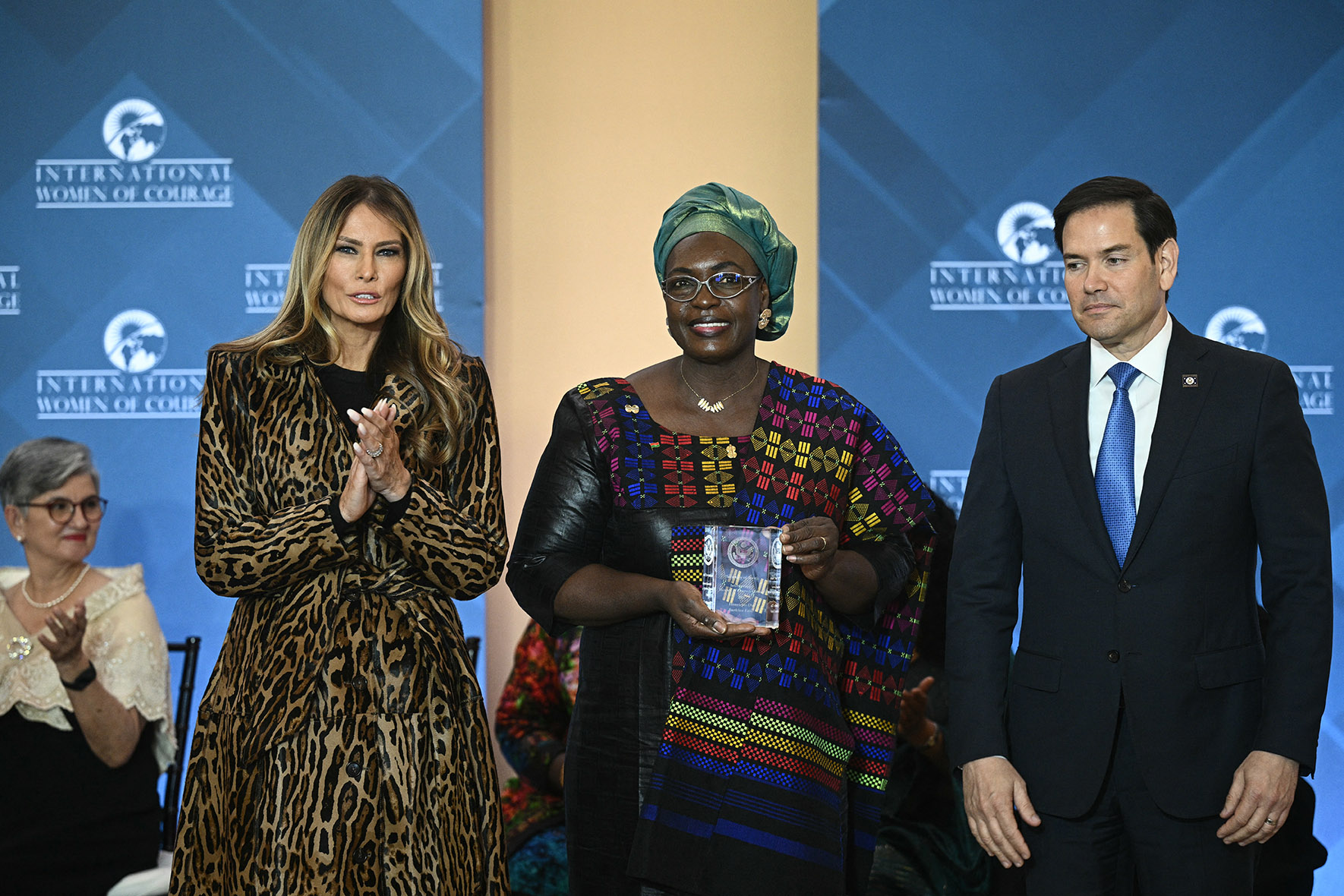 Melania Trump Women of Courage Awards 2025, Milly Park leopard print coat, Henriette Da (C), sociologist and human rights expert from Burkina Faso, is honored by US Secretary of State Marco Rubio (R) and First Lady Melania Trump (L) during the International Women of Courage Awards Ceremony at the State Department in Washington, DC, on April 1, 2025. (Photo by Brendan SMIALOWSKI / AFP) (Photo by BRENDAN SMIALOWSKI/AFP via Getty Images)