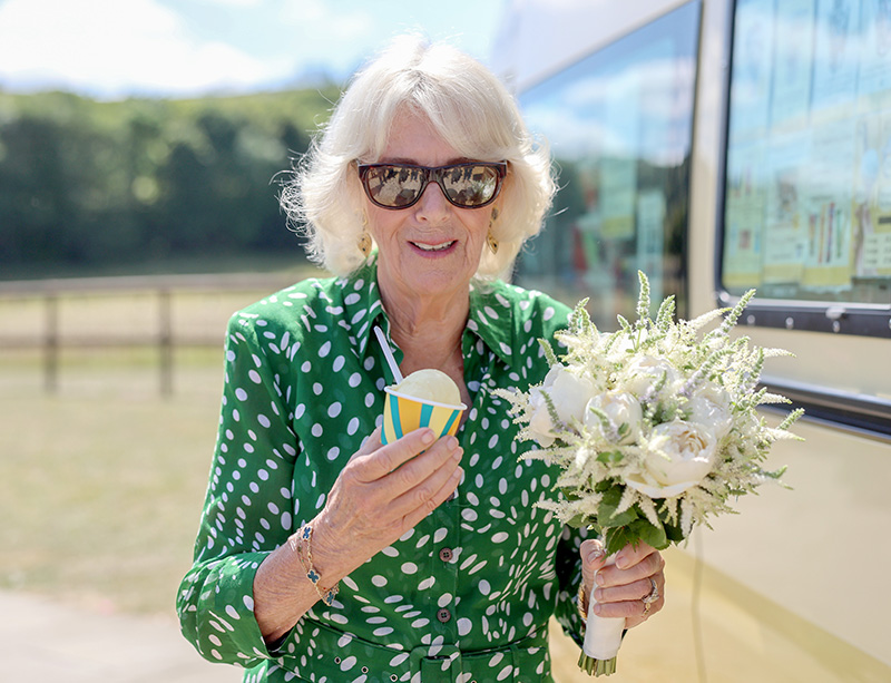 CALNE, ENGLAND - JULY 10: Queen Camilla smiles with a bouquet of flowers and an ice cream from Joanna Weaver's ice cream van during a visit to celebrate the 50th anniversary of the Wiltshire and Swindon Community Foundation at Manor Farm on July 10, 2025 in Calne, England. (Photo by Chris Jackson/Getty Images)